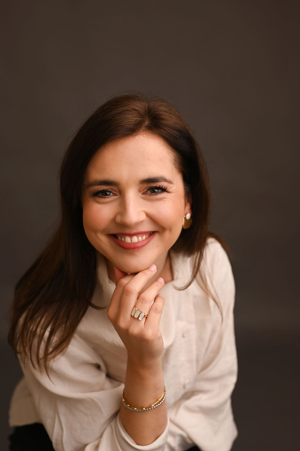 Joana Maciel a sorrir, com a mão junto ao queixo e olhar direto para a câmara.